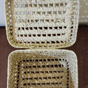 May include: A woven basket with a lid, made of natural materials, with a light beige color. The basket is open and the lid is resting on top.
