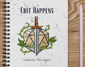 May include: A white notebook with a spiral binding. The cover features a black and white illustration of a sword piercing a twenty-sided die with vines growing around it. The text "Crit Happens (embrace the chaos)" is printed on the cover.