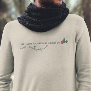 May include: A light beige long-sleeved sweatshirt with the text "All I want for crit-mas is a nat 20" and a red holly berry graphic.