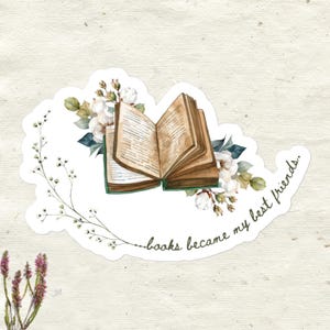 May include: A sticker featuring an open book with aged pages, surrounded by white flowers and green leaves. The text "books became my best friends" is written in a script font, creating a literary theme.