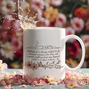 May include: White ceramic mug with a curved handle, featuring a line drawing of two figures and the quote: "Perhaps it is always restful to be around someone who does not expect anything from you beyond what is in your nature." The mug is surrounded by pink flower petals.