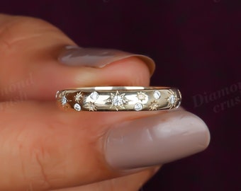 May include: A gold band ring with a row of small diamonds set in a starburst pattern.