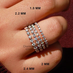 Könnte beinhalten: Fünf Diamant-Eternity-Ringe in verschiedenen Breiten von 1,8 mm bis 2,4 mm. Die Ringe sind auf einem Finger übereinander gelegt und zeigen die unterschiedlichen Größen.