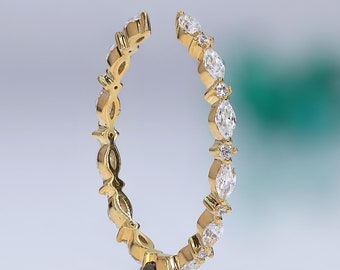 May include: A gold band ring with a row of marquise-shaped diamonds set in a delicate, intricate design.