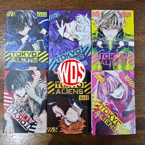 May include: Six colorful manga volumes of Tokyo Aliens, a graphic novel series. The covers feature different characters with vibrant colors and dynamic poses. The titles "Tokyo Aliens" and "Tokyo Aliens R" are visible on the covers.