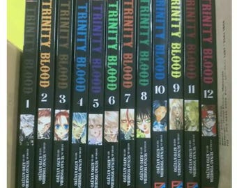May include: A set of 12 manga volumes of Trinity Blood, a dark fantasy series. The spines are black with red, orange, yellow, green, blue, purple, and pink accents. Each volume features a different character from the series.