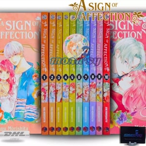 Può includere: Un set completo di 10 volumi manga di "A Sign of Affection" di Suu Morishita. I volumi sono disposti in ordine dal 1 al 10, con ogni volume che presenta una copertina di colore diverso. Le copertine mostrano illustrazioni dei personaggi principali, una giovane donna e un giovane uomo.