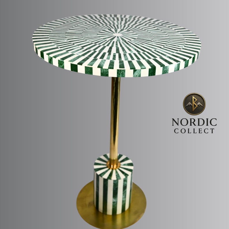 May include: A round side table with a green and white striped top and base. The table has a gold-colored stem and base. The table is 24 inches tall and the top is 18 inches in diameter. The table is from Nordic Collect.