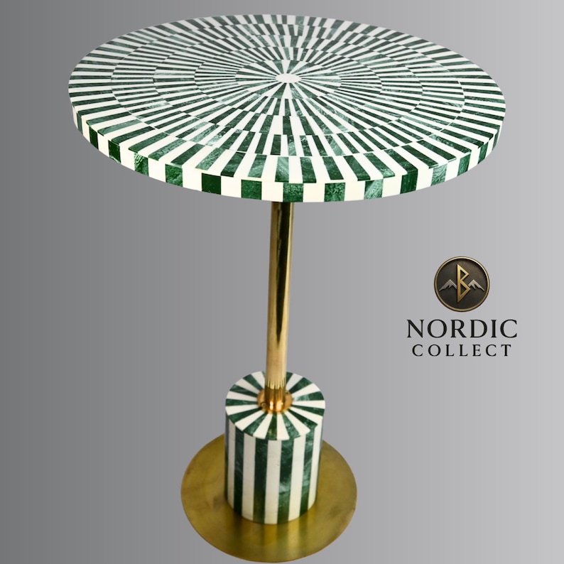 May include: A round side table with a green and white geometric pattern on the tabletop. The table has a gold-colored metal stem and base. The base is cylindrical with matching green and white stripes. The table is approximately 24 inches in diameter.