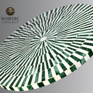 May include: An oval-shaped decorative table with a green and white geometric pattern. The design features concentric circles of alternating stripes and squares, creating a striking visual effect. The table's surface is smooth and reflective, with a glossy finish.