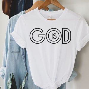 May include: White t-shirt with black text that reads "GOD IS" in a circle design.