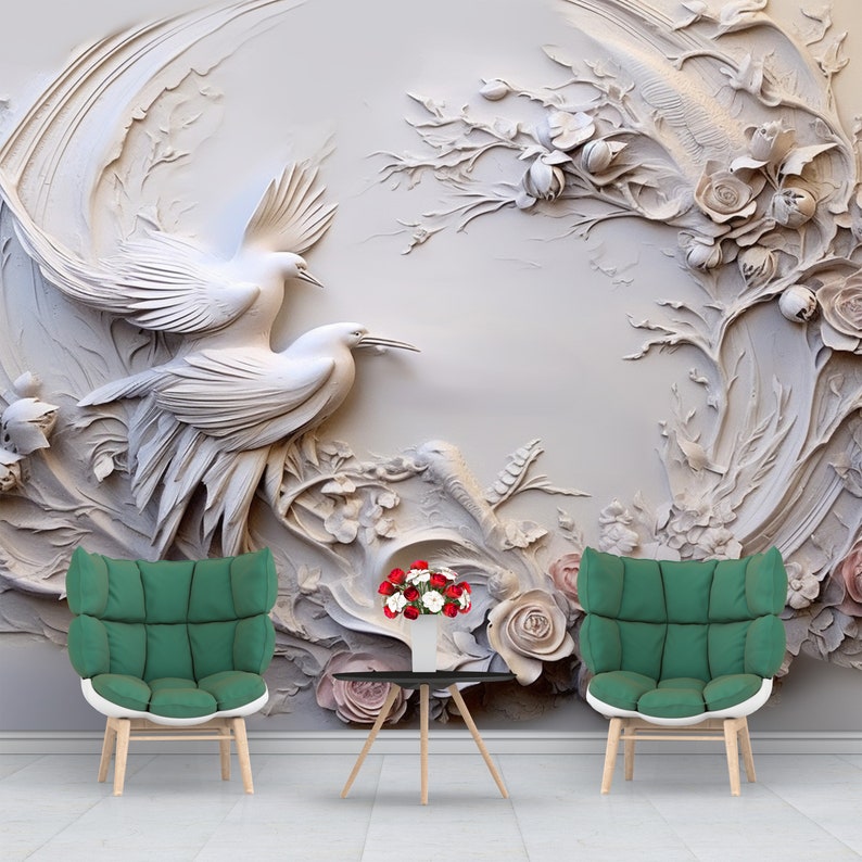 Peut inclure: Une murale murale 3D blanche avec un motif sculpt&eacute; de deux oiseaux et de vignes florales. Deux chaises vertes et une petite table avec un vase de fleurs rouges et blanches sont devant la murale.