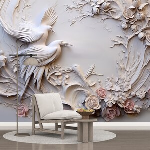Peut inclure: Une murale murale 3D blanche avec un motif floral repr&eacute;sentant deux oiseaux blancs et des roses roses. La murale est expos&eacute;e dans une pi&egrave;ce avec une chaise blanche et une table d'appoint en bois.
