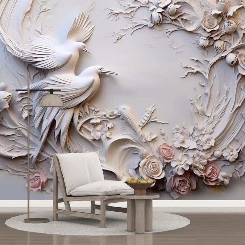 Peut inclure: Une murale murale 3D blanche avec un motif floral repr&eacute;sentant deux oiseaux blancs et des roses roses. La murale est expos&eacute;e dans une pi&egrave;ce avec une chaise blanche et une table d'appoint en bois.