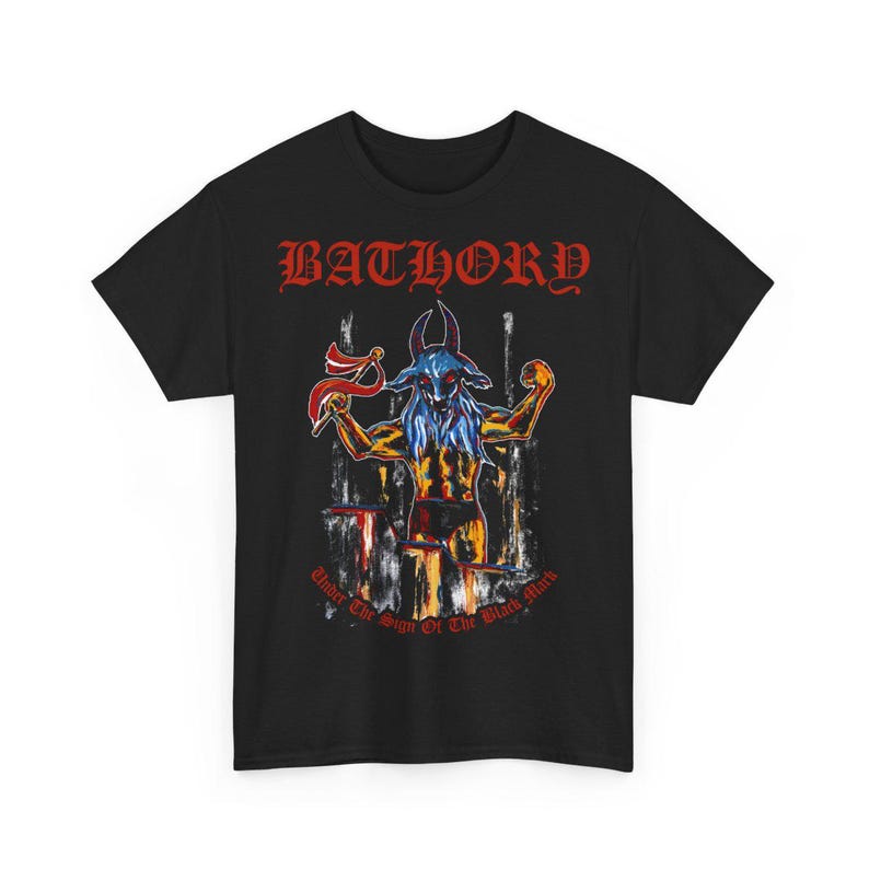 May include: Black t-shirt featuring a red "Bathory" logo and a graphic of a goat-like figure with a blue face and red horns. The text "Under The Sign Of The Black Mark" is printed below the graphic.