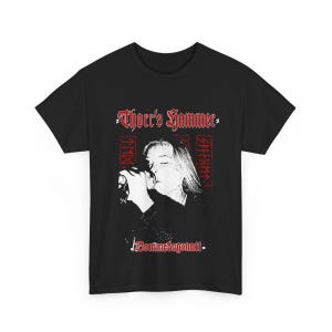 May include: Black t-shirt featuring a black and white image of a person singing into a microphone. The shirt has the text "Thorrs Hammer" in red gothic lettering above the image, and "Dommedagsnatt" below.