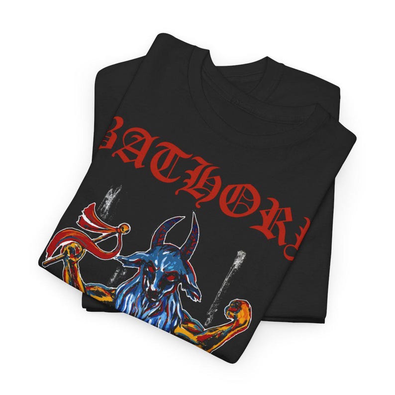 May include: Black t-shirt featuring red "BATHORY" text and a blue and yellow illustration of a goat with horns and a red flag.
