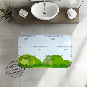 Op de afbeelding: Een blauwe en groene badmat met een natuur scène met bomen en een weg. De mat heeft de tekst "Overlay Mockup PNG" die herhaald wordt over de hele mat.