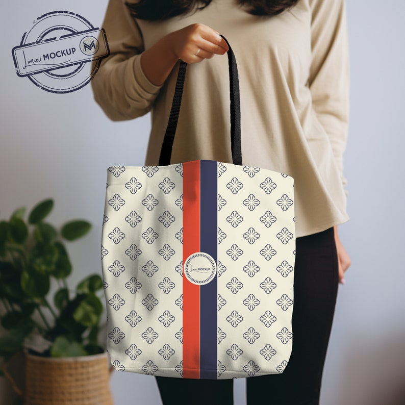 Puede incluir: Una bolsa de tela blanca con asa negra y una franja azul y roja en el centro. La bolsa tiene un patr&oacute;n de peque&ntilde;as flores azules sobre un fondo blanco.