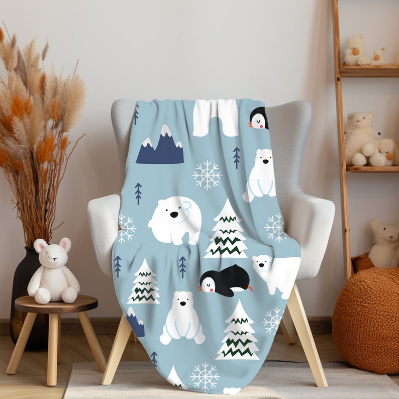 Pu&ograve; includere: Una coperta in pile blu con un motivo di orso polare bianco, pinguino e pino. La coperta &egrave; drappeggiata su una poltrona blu chiaro.