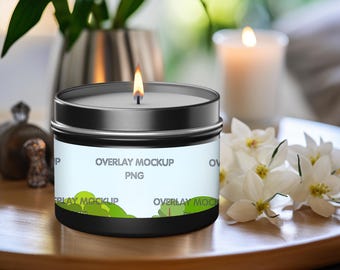 May include: A black candle tin with a white and blue label that says "Overlay Mockup PNG". The label also has a green design of trees and hills. The candle is lit and there are white flowers on a wooden table.