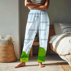 May include: Light blue pajama pants with a white cloud design and green accents at the bottom. The pants have an elastic waistband. The words "OVERLAY MOCKUP PNG" are printed on the pants.