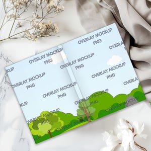 Puede incluir: Una maqueta de portada de libro con un fondo de cielo azul y colinas verdes. El texto "OVERLAY MOCKUP PNG" se repite en toda la imagen.