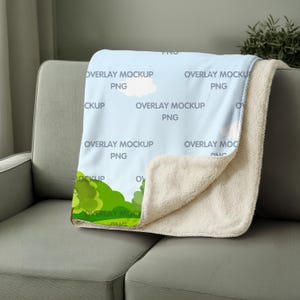 May include: A light blue blanket with a cloud and tree design, labeled "OVERLAY MOCKUP PNG". The blanket has a soft, cream-colored sherpa lining. It is draped over a gray sofa.