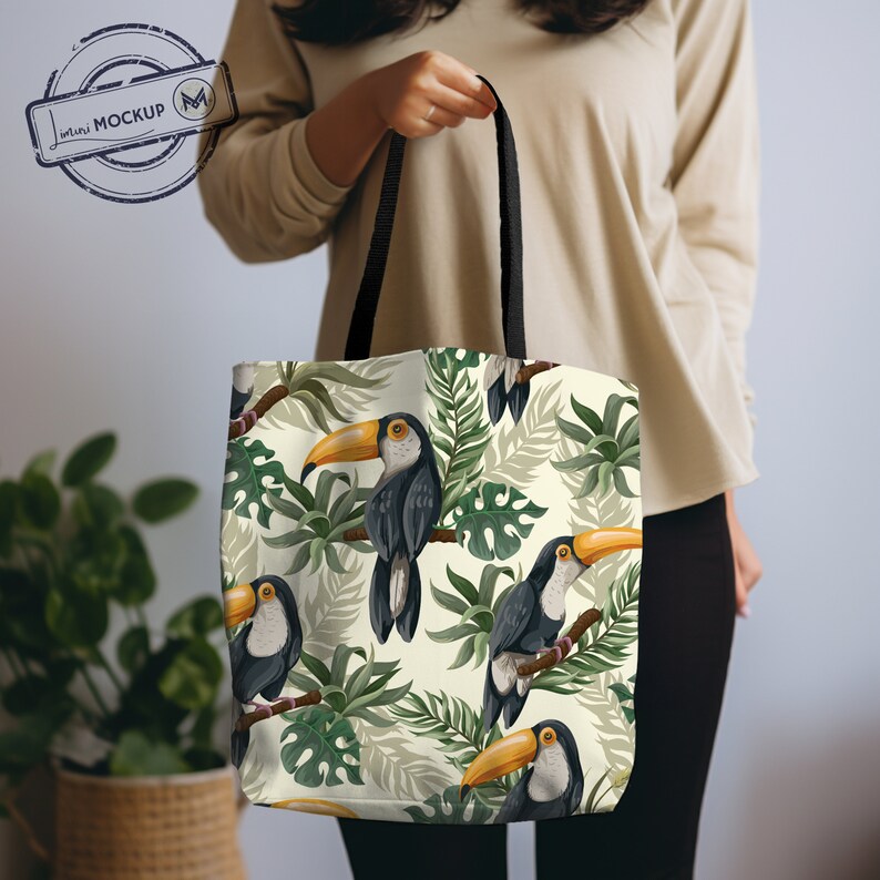 Puede incluir: Una bolsa de tela blanca con correas negras que presenta un estampado tropical de tucanes y hojas verdes.