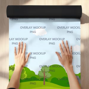 May include: A person is unrolling a sheet of blue paper with a green, yellow, and blue landscape design. The paper has the text "OVERLAY MOCKUP PNG" repeated across the surface.