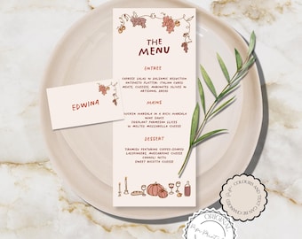May include: A printable menu template with a fall theme. The menu features a handwritten font and illustrations of grapes, leaves, pumpkins, and candles. The menu includes the words "The Menu", "Entree", "Mains", "Dessert", and "Edwinia".