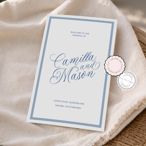 May include: A rectangular wedding invitation card with a light gray background and a blue border. The text reads: WELCOME TO THE WEDDING OF Camilla and Mason GOLD COAST, QUEENSLAND Saturday, 3rd of September. Two circular badges are attached to the side.