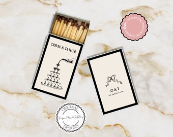 May include: A set of two matchboxes with custom designs. The first matchbox features a black and white illustration of a champagne tower with the text "Olivia & Taylor". The second matchbox features a black and white illustration of a bow with the text "O&T" and the date "19th September 2020".