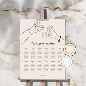 May include: A black and white wedding seating chart with the text "Your seat awaits". The chart is divided into twelve sections, each with a number and a list of names. The chart is decorated with a hand-drawn illustration of two hands holding cards with the names "Declan" and "Elise" written on them.