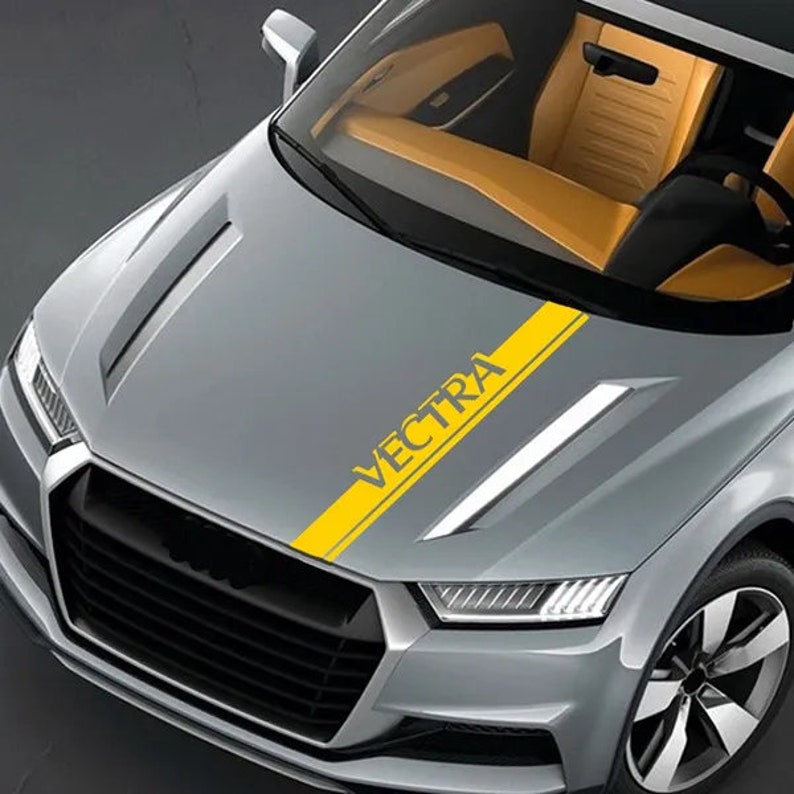 May include: A grey car bonnet featuring a yellow stripe with the word "VECTRA" in a matching font. The car has a modern design, with a yellow interior visible through the windscreen.
