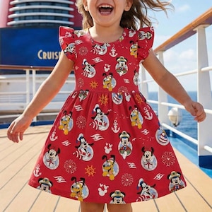 Puede incluir: Vestido rojo con un estampado de Mickey Mouse, Pluto y Goofy en diseños náuticos. El vestido tiene mangas cortas con volantes y una falda acampanada. La palabra "CRUIS" es visible en el fondo.
