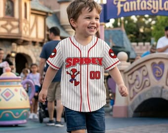 Op de afbeelding: Een wit en rood gestreept honkbalshirt met het woord "SPIDEY" in rode blokletters over de borst. Het shirt heeft een cartoon Spider-Man afbeelding en het nummer "00". Het shirt wordt door een kind gedragen.