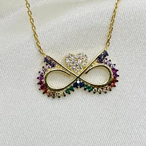 May include: A gold necklace featuring an infinity symbol pendant with a rainbow of cubic zirconia stones and a small heart charm.