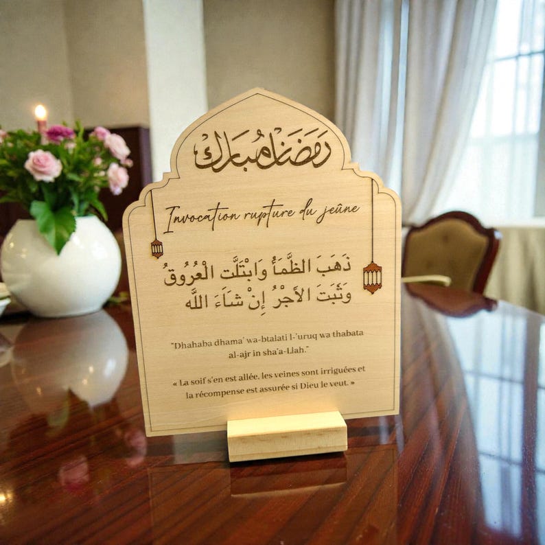 May include: A light-colored wooden sign with an arched top, featuring engraved Arabic calligraphy, the text "Invocation rupture du je&ucirc;ne," and the transliterated and translated prayer for breaking the fast, supported by a rectangular wooden base.