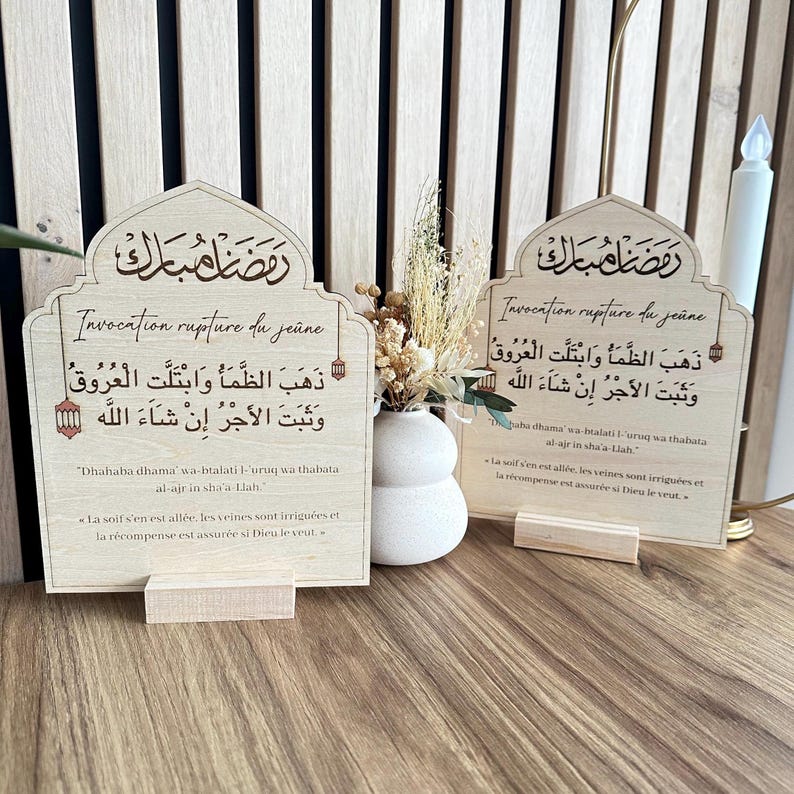 May include: Two arched light-colored wooden plaques featuring Arabic calligraphy and French text titled Invocation rupture du je&ucirc;ne. The plaques include the phrase Dhahaba dhama wa-btalati l-uruq wa thabata al-ajr in sha-a-Llah and its French translation.