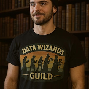 May include: Black t-shirt with a retro design featuring the words "DATA WIZARDS GUILD" above silhouettes of figures with laptops and staffs. The design has a sunset color scheme. The person in the image is wearing a black beanie.