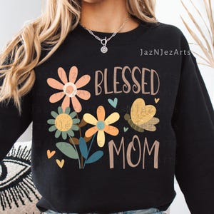 May include: Black sweatshirt with a floral design and the words "BLESSED MOM". The design includes flowers in peach, yellow, and blue, a butterfly, and small blue and yellow hearts.