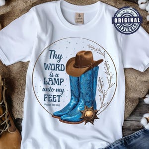Peut inclure: T-shirt blanc avec un motif graphique représentant un chapeau de cowboy marron et des bottes de cowboy bleues dans un cadre circulaire. Le texte "Thy WORD is a LAMP unto my FEET Psalm 119:105" est également inclus.