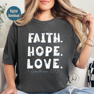 May include: A dark gray t-shirt with a distressed white graphic that reads "FAITH. HOPE. LOVE. 1 Corinthians 13:13".