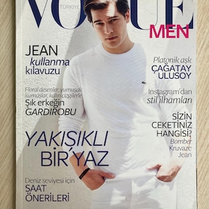 Puede incluir: Una portada de revista "Vogue Men" con un hombre vestido de blanco. El texto incluye "Jean kullanma kılavuzu" y "YAKIŞIKLI BİR YAZ".
