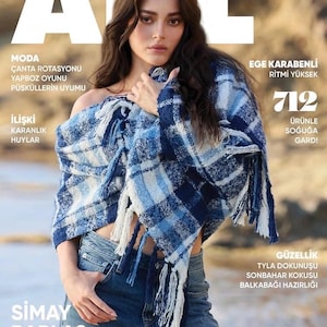 Puede incluir: Portada de revista con una mujer con un chal a cuadros azul y blanco con flecos, y vaqueros azules. La revista se titula "ALL" con texto en turco. La portada también presenta el nombre "Simay Barlas".