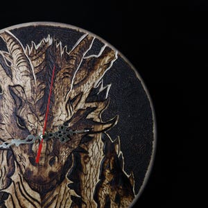 Puede incluir: Un reloj de madera redondo con un diseño detallado de dragón. El dragón está tallado en la madera y es de color marrón oscuro. Las manecillas del reloj son plateadas con un segundero rojo. El fondo es negro.