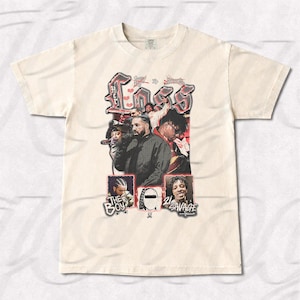 Puede incluir: Camiseta de color crema con un diseño gráfico con la palabra "Her Loss" en una fuente estilizada. El diseño incluye imágenes de varias personas. La parte inferior de la camiseta tiene el texto "The Boy" y "21 Savage".