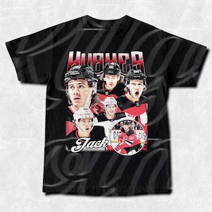 May include: Black t-shirt with a vintage-style graphic of hockey players wearing red and black jerseys. The text "Hughes" and "Jack" are featured on the shirt.
