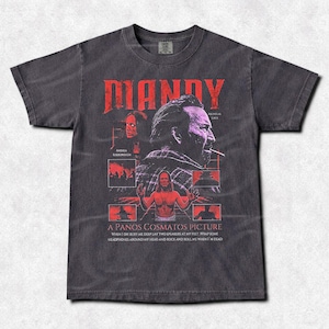 May include: Dark gray t-shirt featuring a red graphic design with the title "MANDY" and images of a man and other figures. The text "A PANOS COSMATOS PICTURE" is also visible. The shirt has a vintage, distressed look.